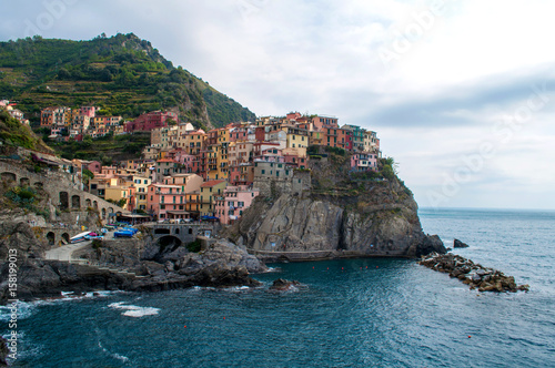 Manarola Italy - colorful houses on a rock above the sea with a small harbor in the Cinque Terre region of Italy.