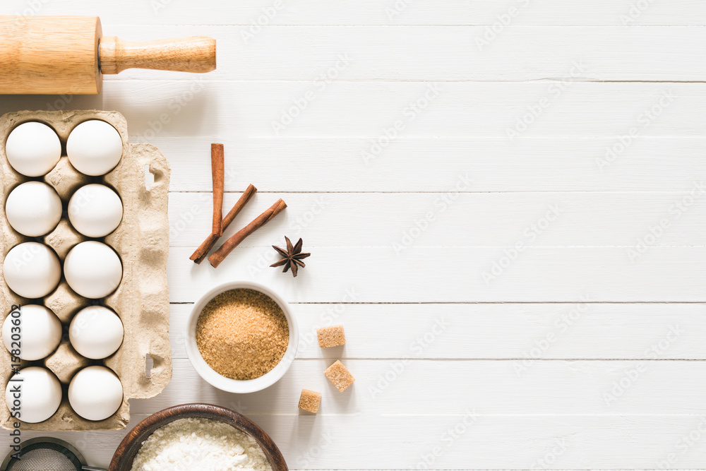 Baking ingredients on white wood with copy space. Eggs, brown sugar, white  flour, spices and rolling pin on white wooden background. Top table top  view. Cooking, baking background, recipe mock up Stock