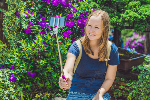 young beautiful girl doing selfie mobile phone in the park on summer day photo