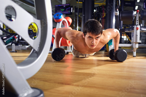 A man does push-ups from floor in the gym.