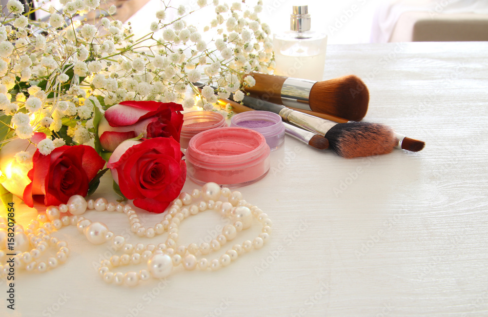 beautiful roses next to makeup and perfume on wooden background. beautiful roses next to makeup and perfume on wooden background.