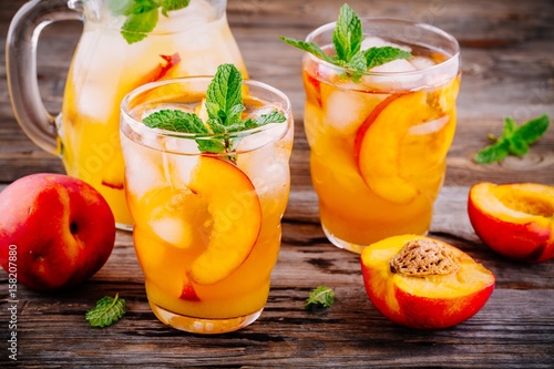 Foto Summer cold drinks: homemade peach sangria with ice cubes, and mint in glasses