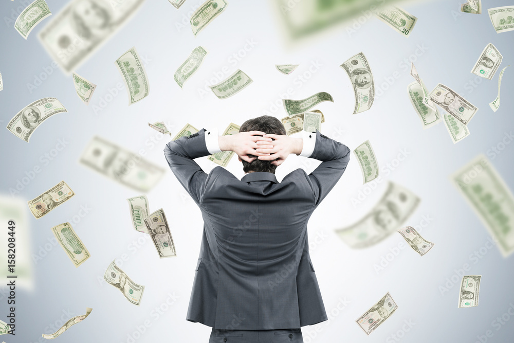 Businessman with hands behind head in money flow Businessman with hands behind head in money flow