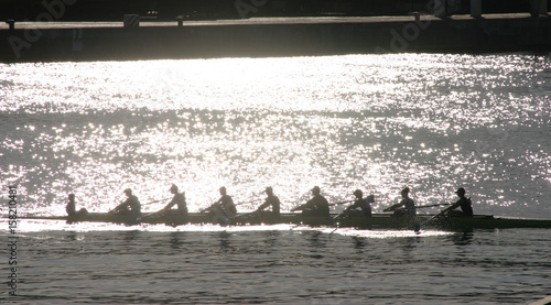 Silhouetted athletes rowing at sunset