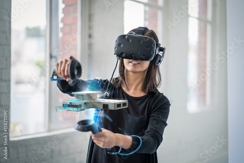 A woman wearing a virtual reality headset interacts with 3D objects. © db
