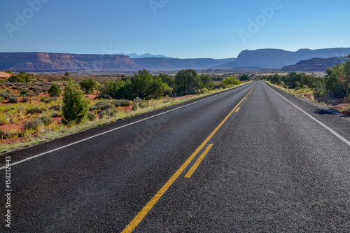 empty country road in grasslands with flat top mountains in the background UT-211 Scenic Highway, Canyonlands National Park, Utah, United States