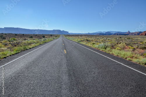empty country road in grasslands with flat top mountains in the background UT-211 Scenic Highway, Canyonlands National Park, Utah, United States