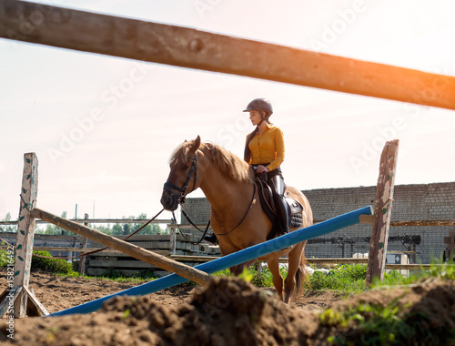 Young cheerful girl rides on a brown horse. Riding training. Horseback Riding.