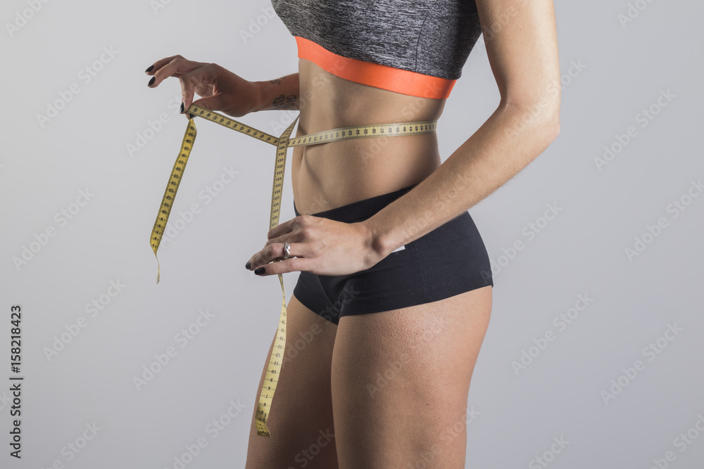 Foto de Mujer delgada con cinta métrica en la cintura do Stock