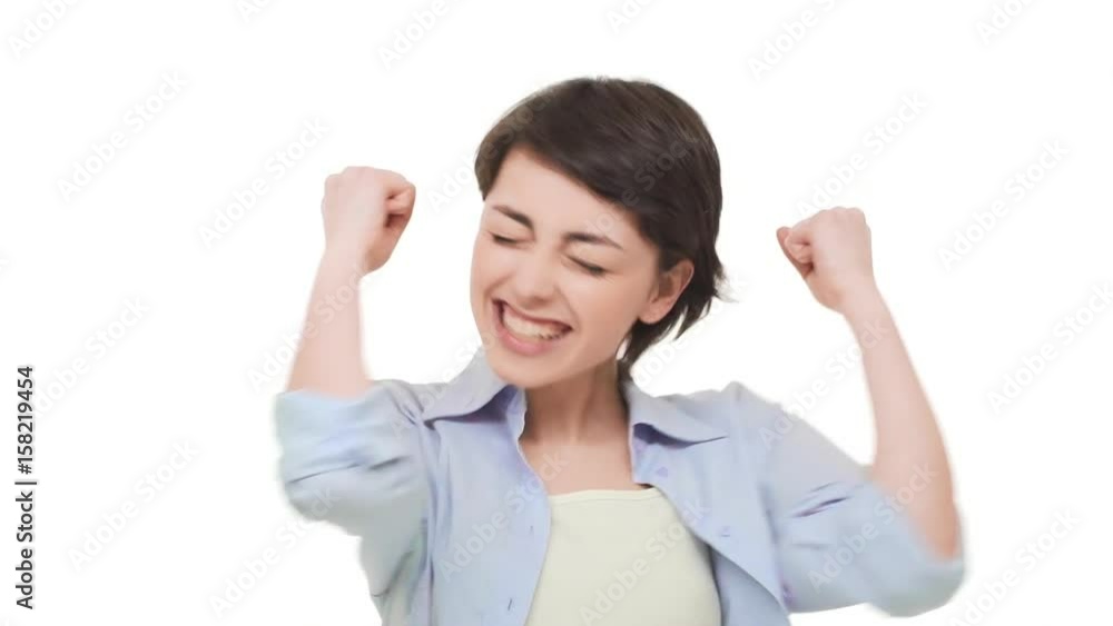 Happy beautiful female with short brunette hair rejoicing and saying yes over white background in slowmotion Happy beautiful female with short brunette hair rejoicing and saying yes over white background in slowmotion