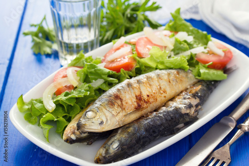 grilled sardines with salad on white dish