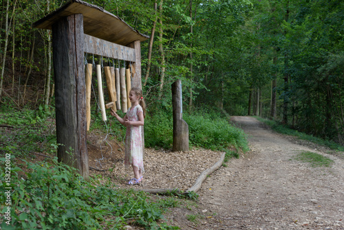 Child making music on a instrument at a sensory path in the forest