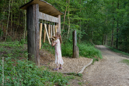 Child making music on a instrument at a sensory path in the forest