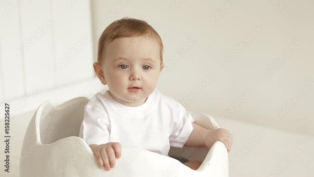 A small baby is sitting in a toy egg shell. little cute baby A small baby is sitting in a toy egg shell. little cute baby