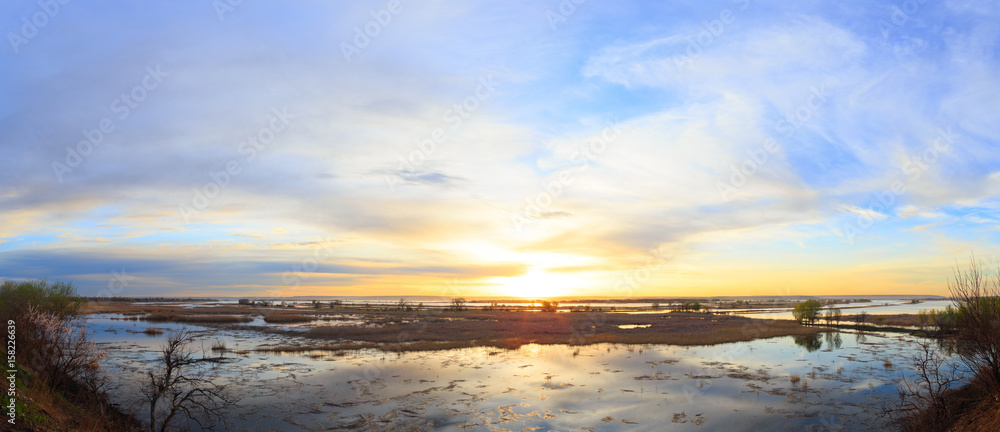 Sunset on Volga river, beautiful spring landscape with cloudy sky. Panorama of landscape.