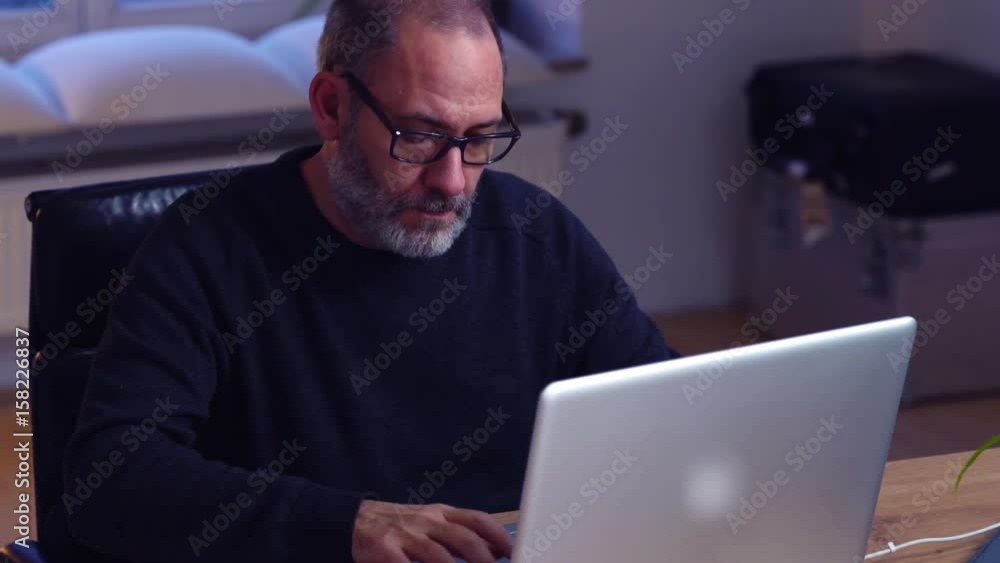 attractive businessman using laptop computer on wooden desktop in stylish office attractive businessman using laptop computer on wooden desktop in stylish office
