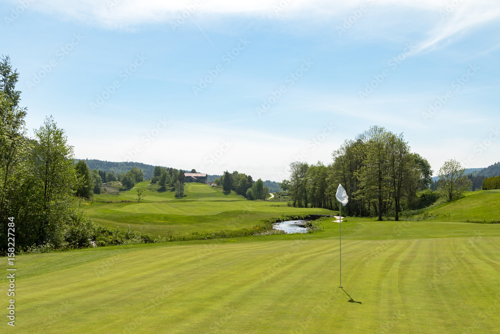 Golf course. Hole with a white flag on a sunny day