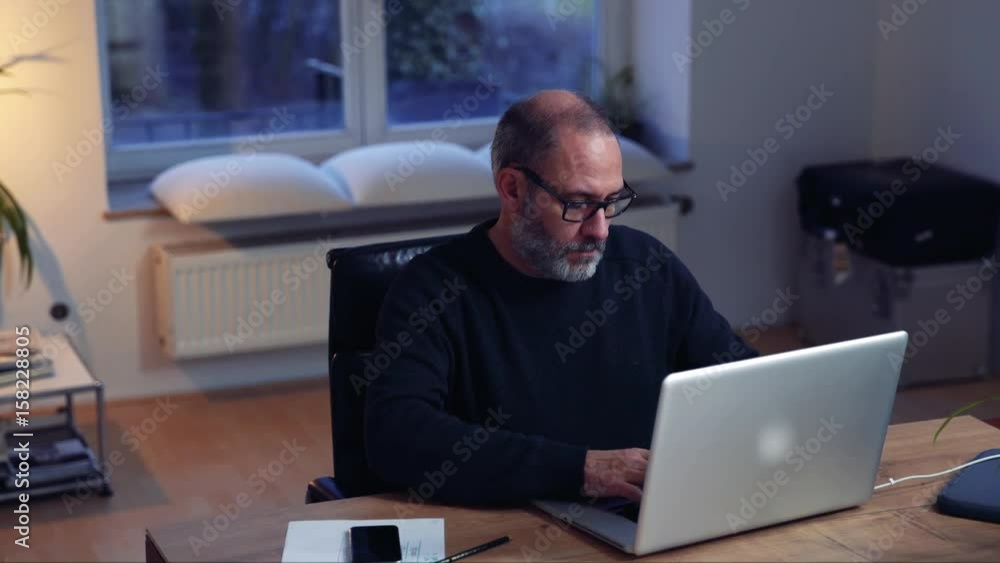 attractive businessman using laptop computer on wooden desktop in stylish office attractive businessman using laptop computer on wooden desktop in stylish office