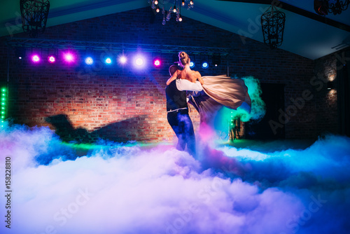 Wedding party: first dance of the bride and groom. The smoke and the light show around