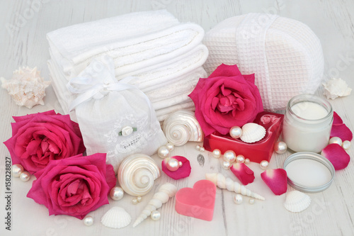 Rose flowers with skincare beauty treatment products and cleansing ingredients with seashells and pearls on distressed white wood background.