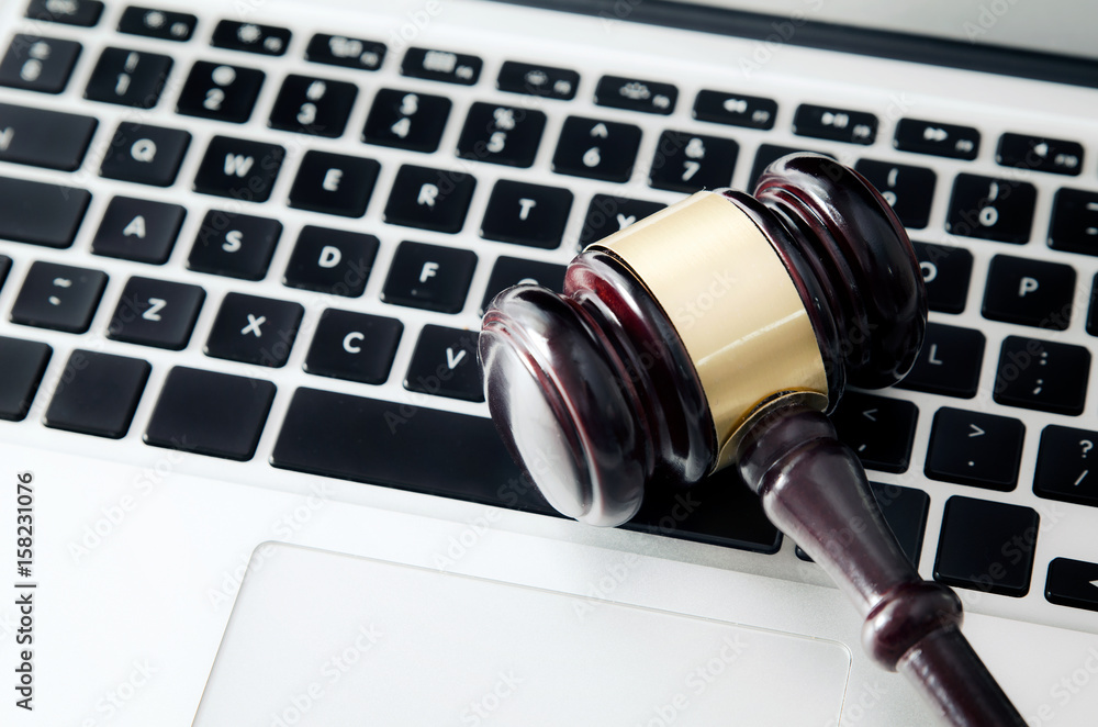 Wooden gavel on laptop keyboard Wooden gavel on laptop keyboard