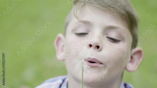 Boy blowing dandelion seedhead in slow motion photo