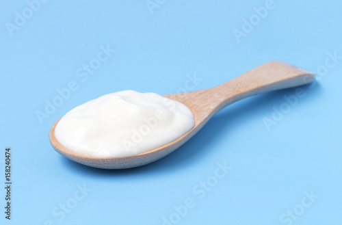 Greek yogurt on wood spoon with blue background