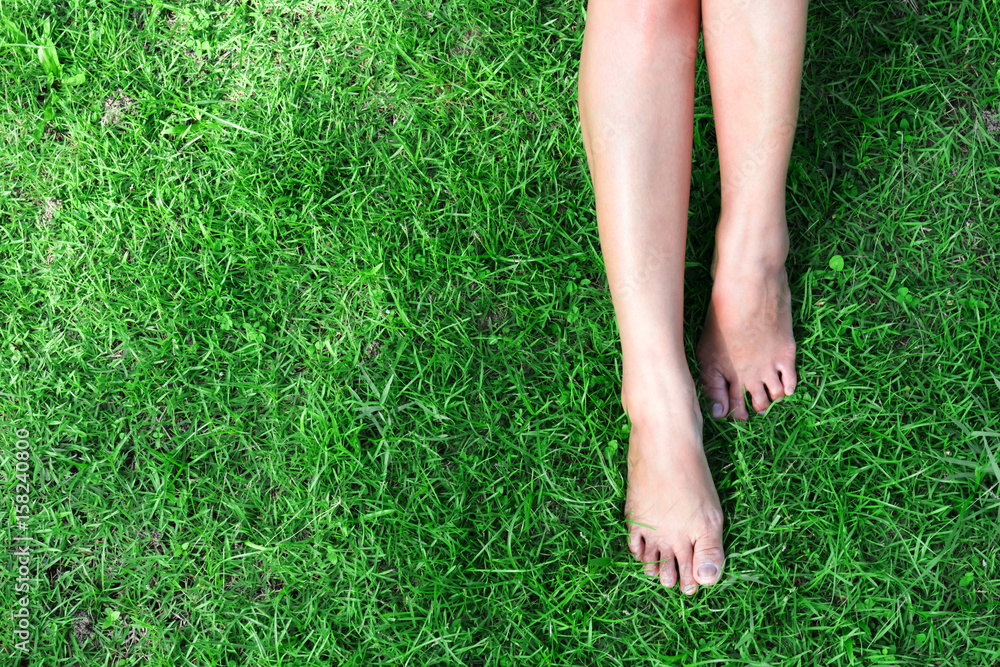 Woman legs relax feeling on green grass background with light of sun