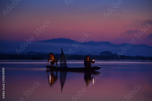 Silhouette fisherman are moveing to fishing on before sunrise,during sunrise,Thailand