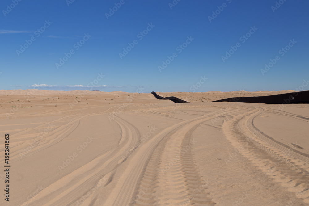 Naklejka premium U.S. / Mexico border wall stretching along Imperial Sand Dunes