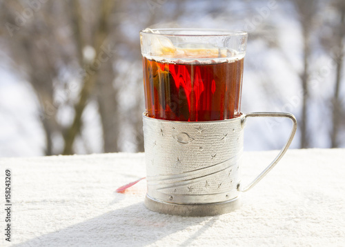 Hot tea in a faceted glass against the background of winter nature