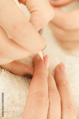 Beautician preparing nails before manicure, pushing back cuticles