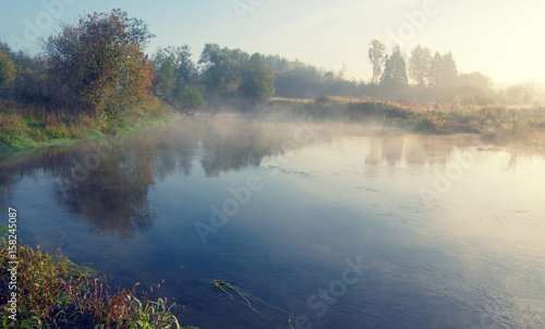 Foggy autumn landscape with small river