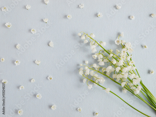 Lily of the valley on a blue paper textured background. Pattern of small flowers of the may-lily. Abstract floral background.