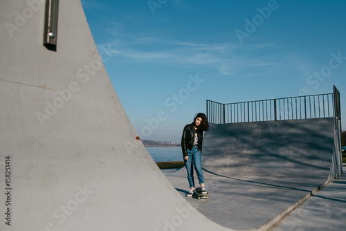 Awesome skateboarder girl with skateboard outdoor at skatepark. Skatebord at city, street. Cool, Funny Tenager. photo