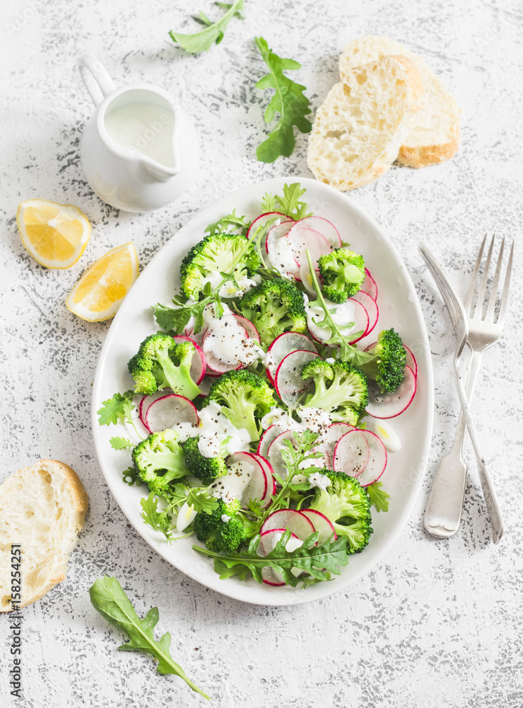 Spring broccoli and radish salad with yogurt sauce on a light background, top view. Delicious healthy vegetarian food concept Spring broccoli and radish salad with yogurt sauce on a light background, top view. Delicious healthy vegetarian food concept