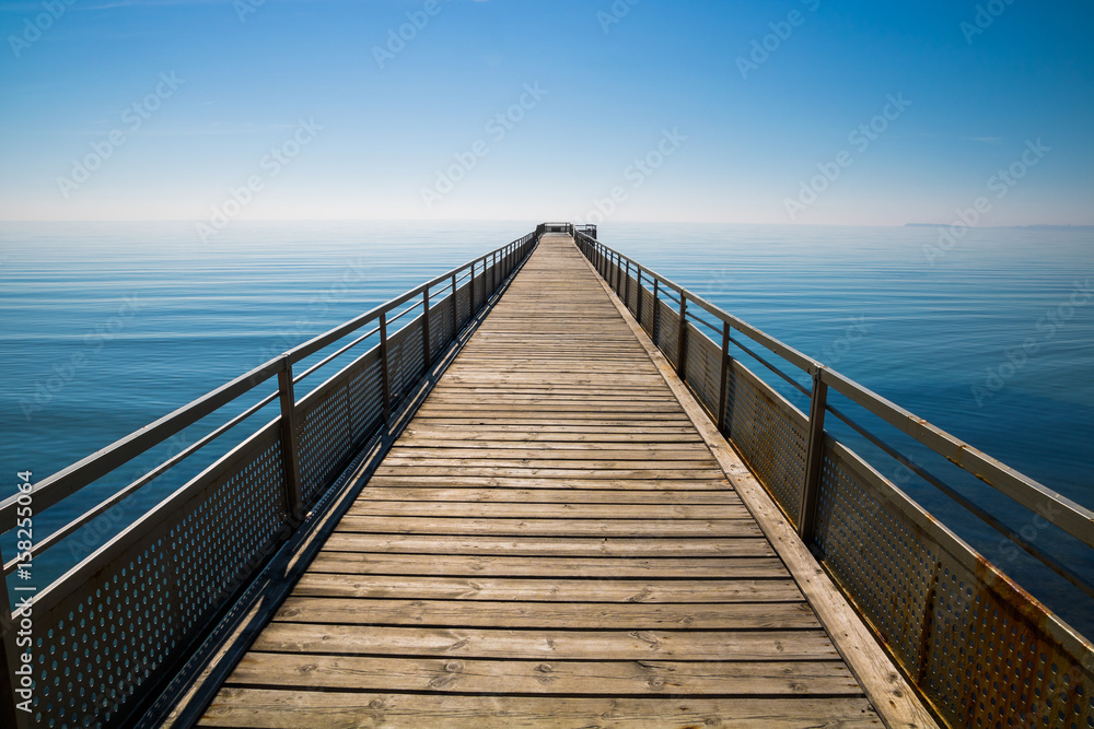 A path to infinity. Long seaside pier reaching the sky.