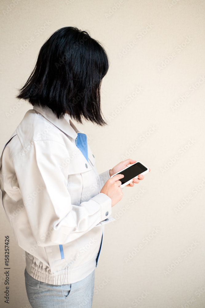 スマートフォンを操作する女性作業員 スマートフォンを操作する女性作業員