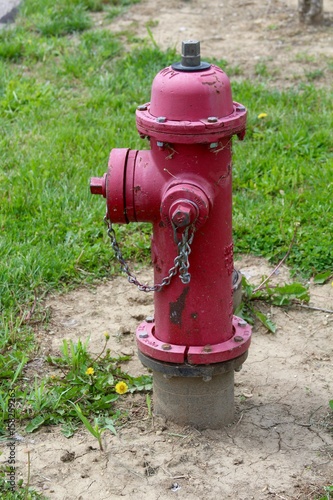 The red fire hydrant in the grass on a close up view.