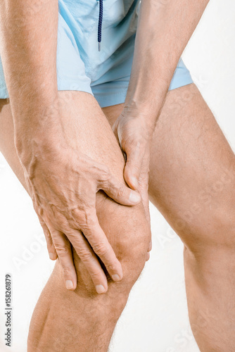 Athlete man feeling pain to the knee and the quadriceps. It could be Iliotibial band syndrome or quadriceps tendinopathy photo