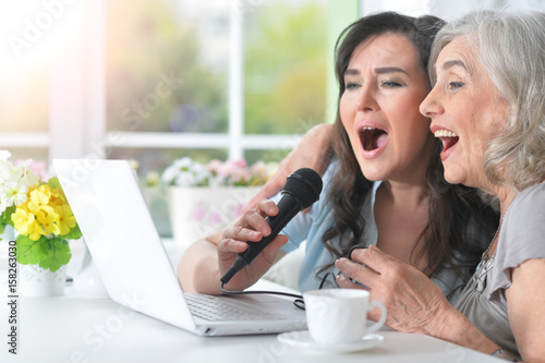 Two elderly girlfriends sing 