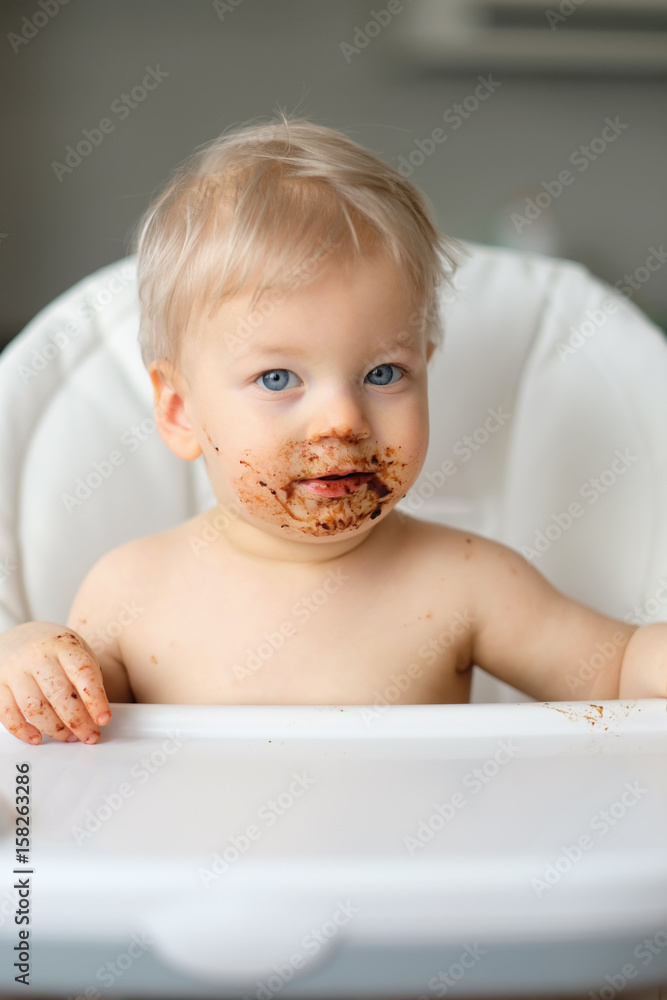 Toddler baby boy child eating fruit with dirty messy face Toddler baby boy child eating fruit with dirty messy face