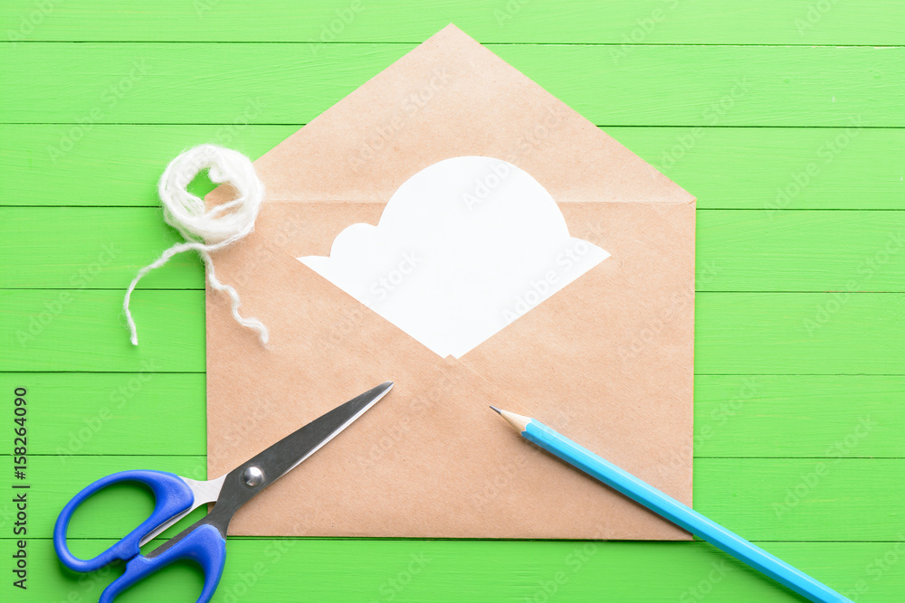 White sticker in the shape of clouds in the envelope on green wooden background White sticker in the shape of clouds in the envelope on green wooden background