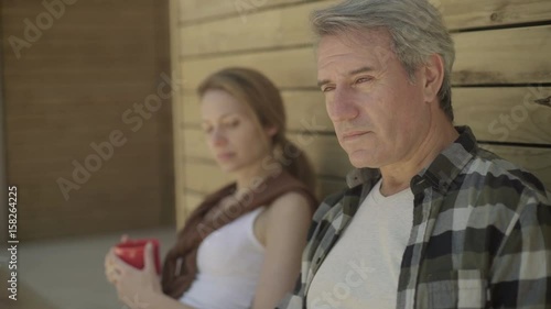 Couple drinking coffee outside of cabin photo