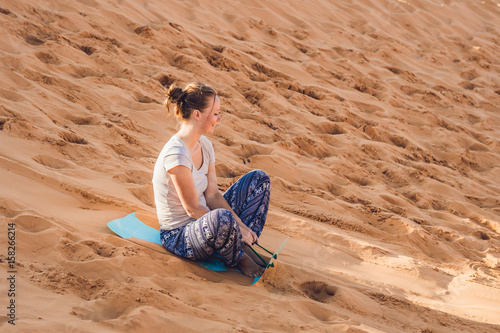 Young woman rolls on a toboggan in the sledge in the desert photo