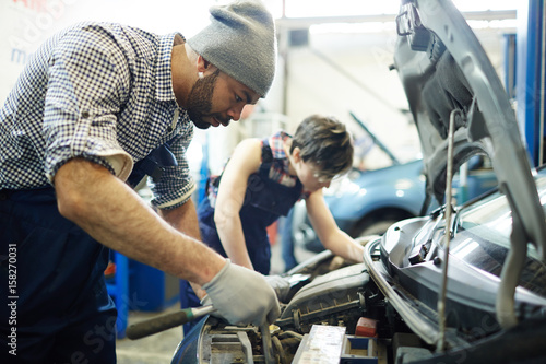 Car service technician repairing engine