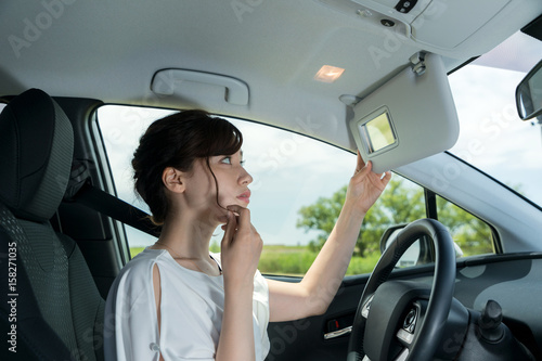 woman driver checking her face by sun visor mirror.