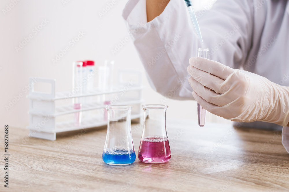 Doctor testing samples with pipette in glass container. Doctor testing samples with pipette in glass container.