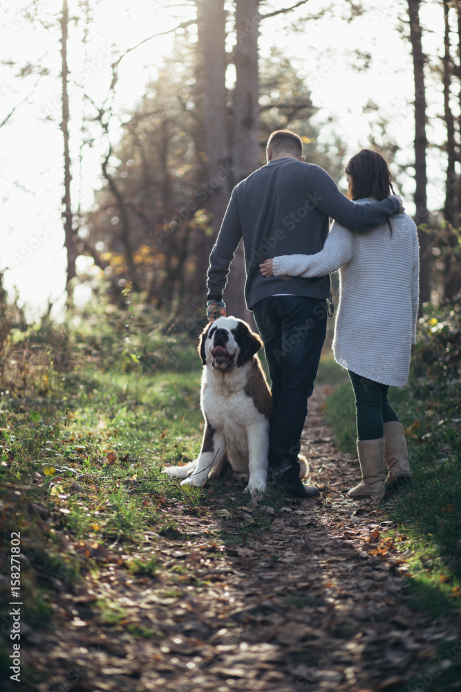 Young couple enjoying nature outdoors together with their Saint Bernard puppy. Young couple enjoying nature outdoors together with their Saint Bernard puppy.