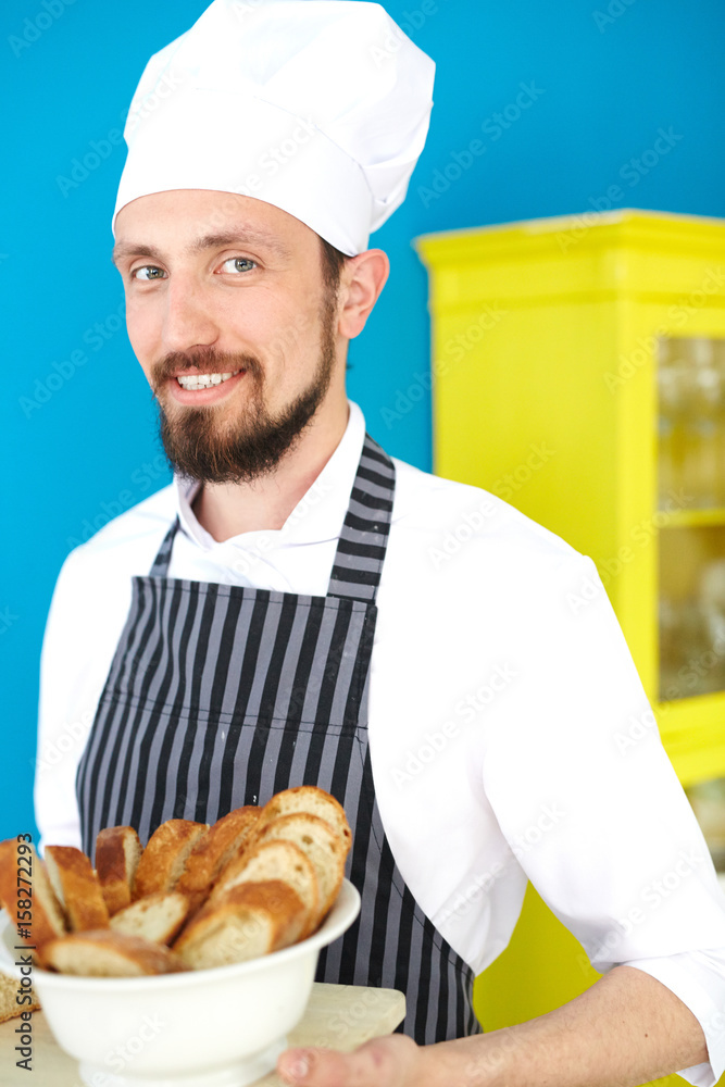 Smiling baker holding plate with sliced bread Smiling baker holding plate with sliced bread